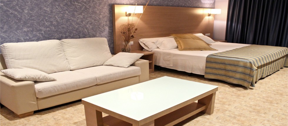 Habitación extra grande con una cama extra grande de 2 metros x 2 metros. Sofá de dos plazas y mesa de centro.